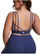 Person wearing a blue sports bra and leggings with a geometric back design on a plain background